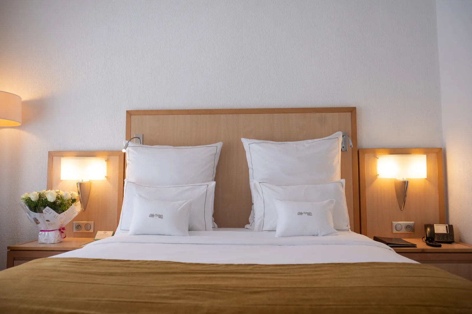 Lit double de la Chambre Standard vu de face, linge blanc et jeté de lit doré