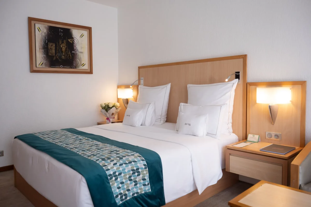 Chambre Supérieure de l'Hôtel TIAMA à Abidjan : lit double, jeté bleu canard et tableau