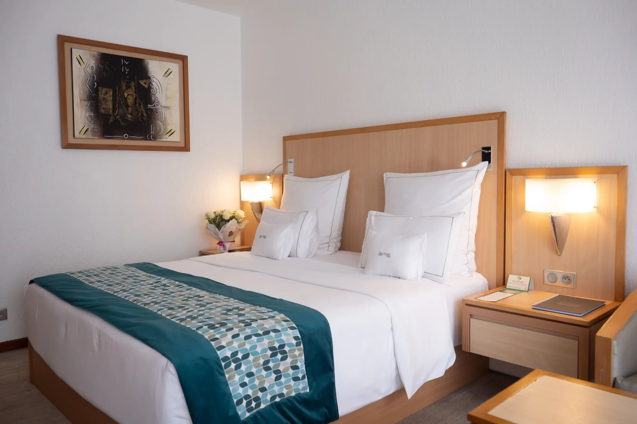 Chambre Supérieure de l'Hôtel TIAMA à Abidjan : lit double, jeté bleu canard et tableau