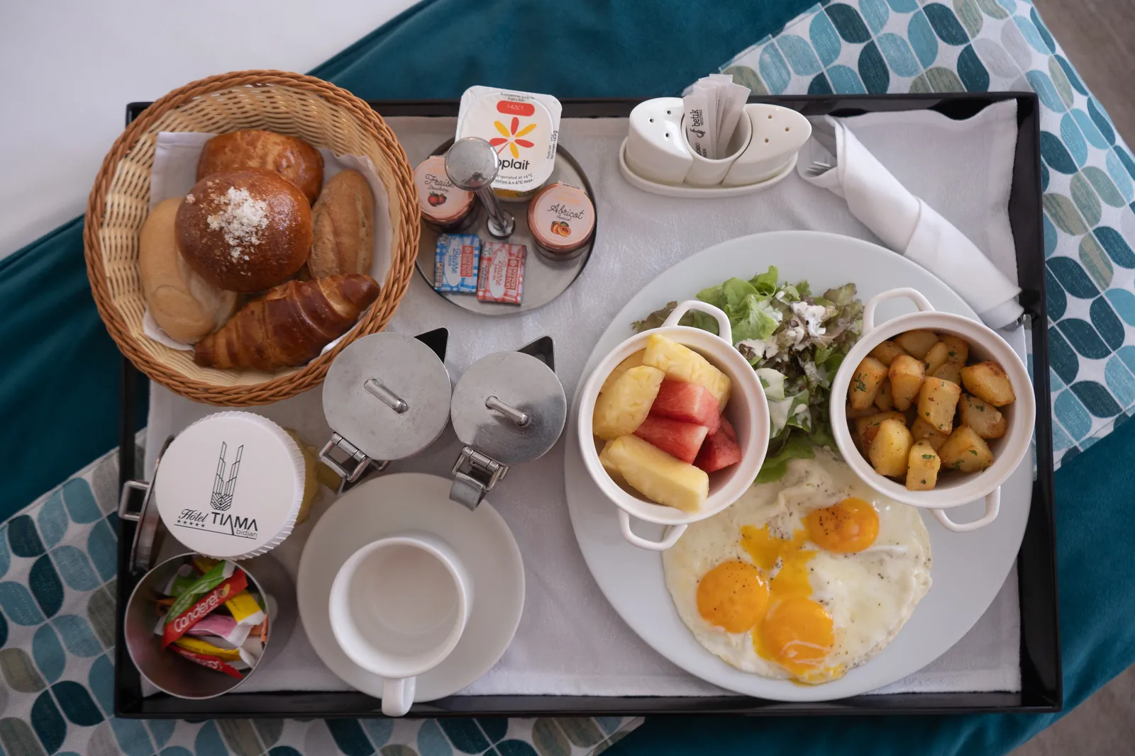 Petit-déjeuner complet vu de dessus : viennoiseries, œufs et fruits