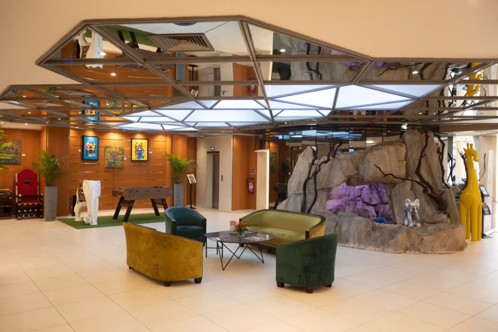 Lobby de l'Hôtel TIAMA à Abidjan : salon sous verrière et décor de roche