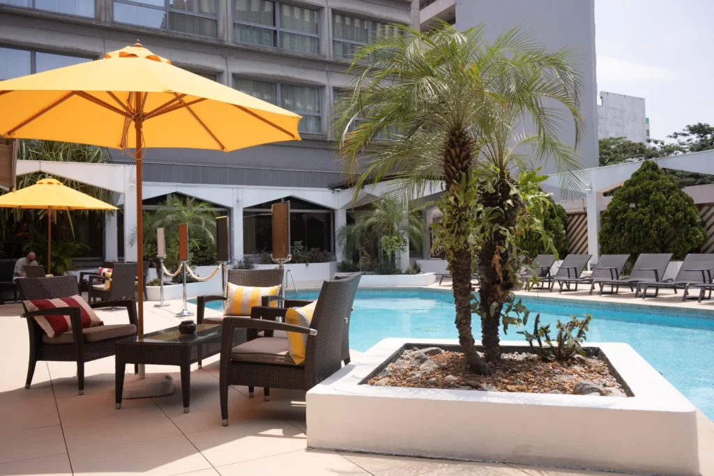Terrasse de la piscine : salon de jardin, parasol et palmier