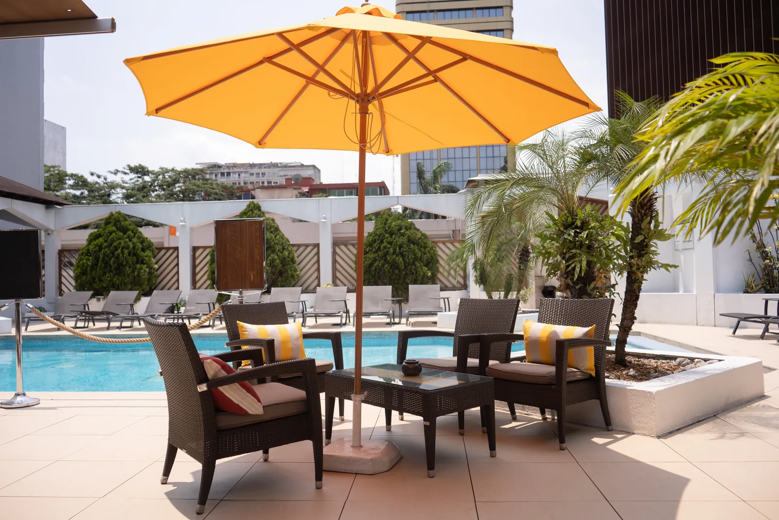 Salon de jardin sous parasol au bord de la piscine