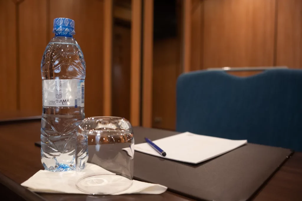 Détail de table de réunion : eau, verre et bloc-notes