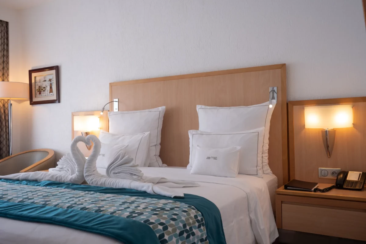 Suite Junior de l'Hôtel TIAMA à Abidjan : lit double et cygnes en serviettes